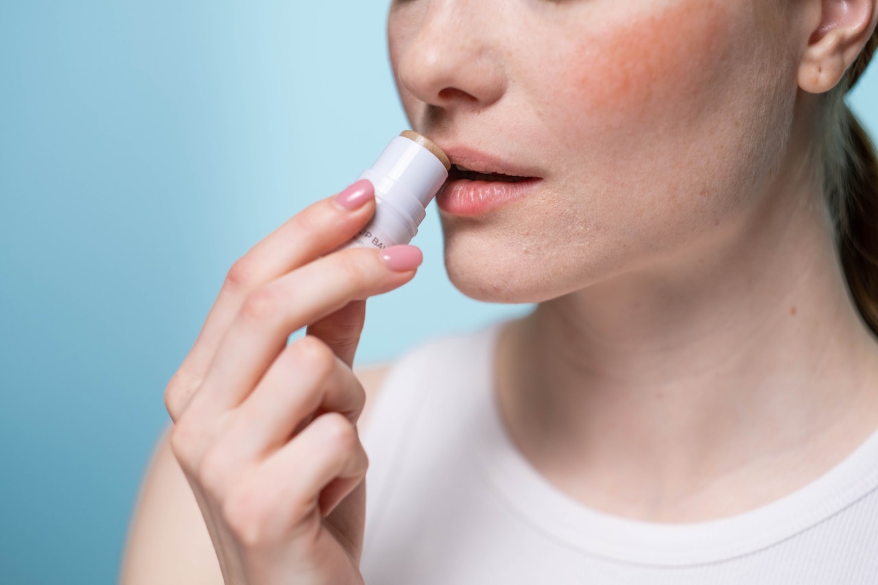 crop photo of a woman using a lip balm